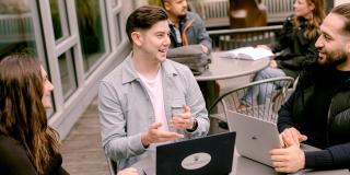 Students sitting at a table outside with a laptop