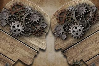 Human silhouettes facing each other with turning gears in their heads