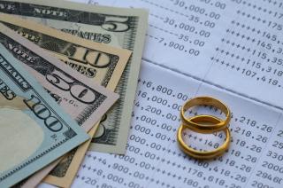 Wedding rings and money on top of a monthly bill